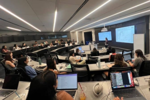 four people smiling in white lab coats, two shaking hands