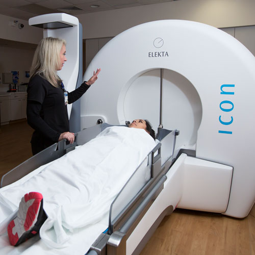 A woman smiling down at a patient entering the Elekta radiosurgery system