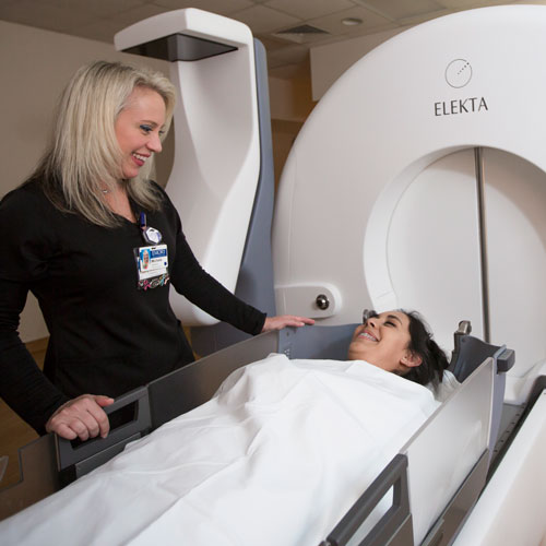 Woman smiling down at a patient about to enter the Elekta Icon radiosurgery system