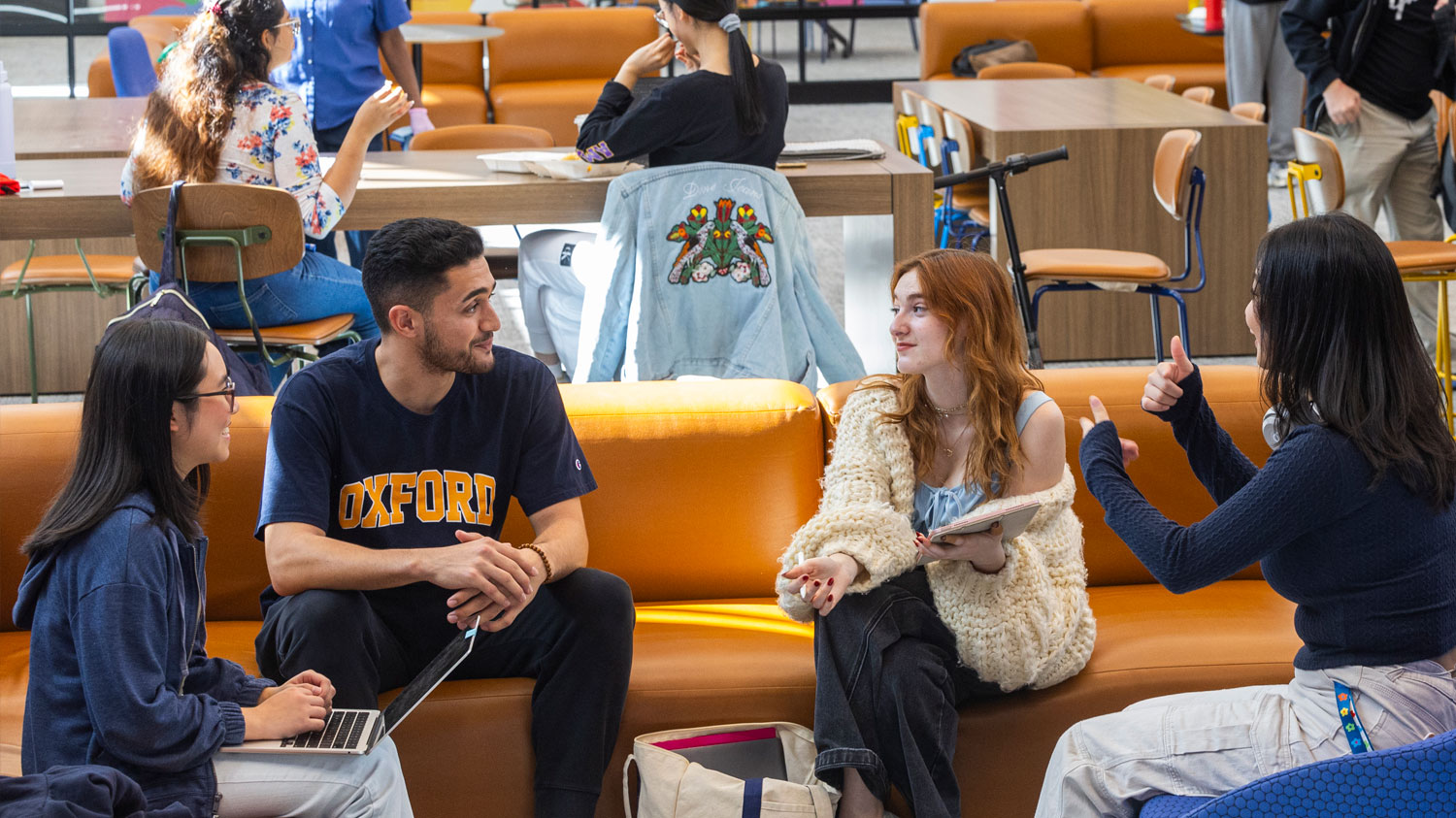 four students having a lively conversation in a study hall