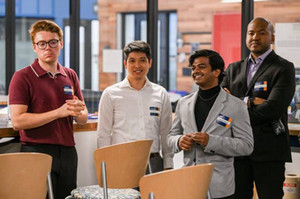 four people smiling in white lab coats, two shaking hands
